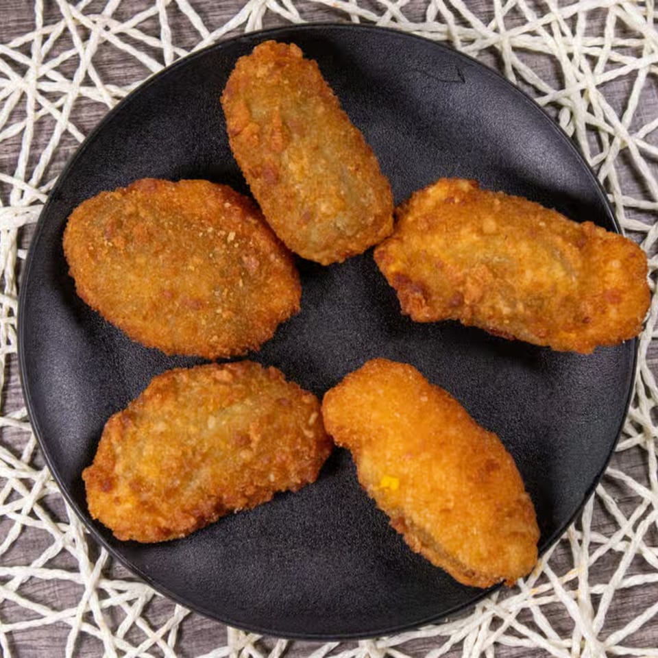 Five golden-brown, crispy fried Mexican appetizers arranged on a black plate.